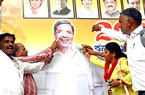 Supporters of senior Congress leader Siddaramaiah perform 'abhishek' of his poster during ...