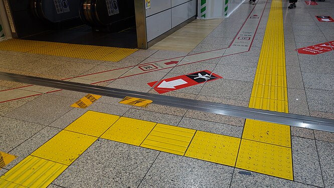 Tactile paving in Tokyo Station, Japan. Unlike the floor signs for the people without visual impairment, the tactile paving indicate a jagged route.