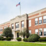 The front of a grade school with shrubs and a lawn in front.