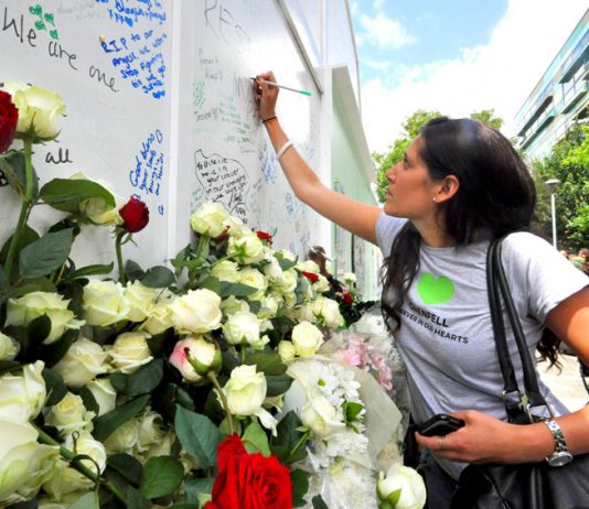 Writing tributes on the memorial at the base of Grenfell Tower yesterday