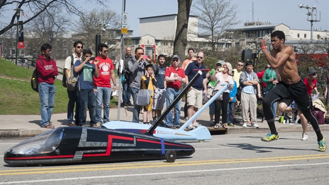 male student pushing a buggy uphill