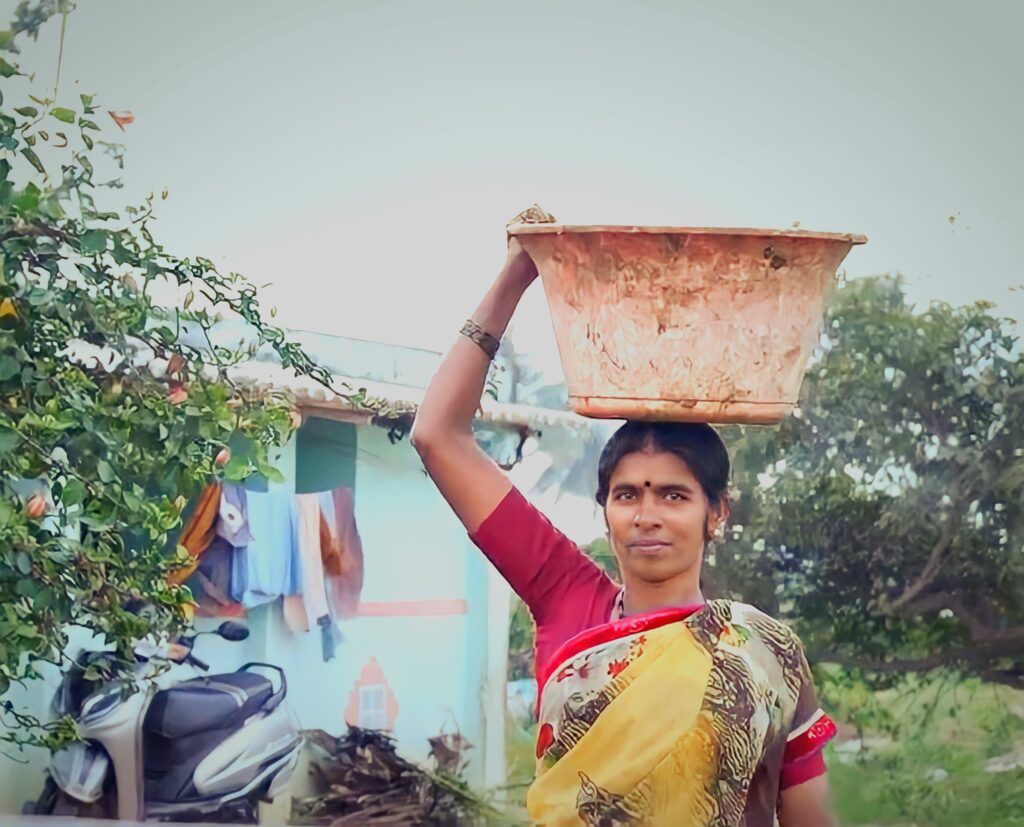 a female dairy farmer is holding a pot in the rural district of Kolar in Karnataka, India