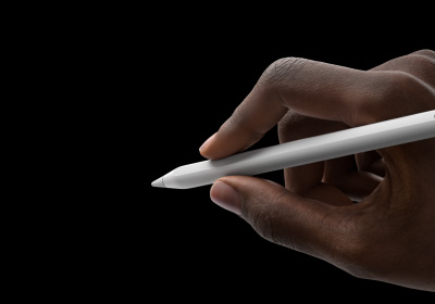 Una mano sostiene un Apple Pencil Pro en posición para escribir. La punta está orientada hacia una interfaz que muestra una nueva paleta de herramientas.