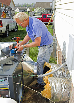 Male HVAC technician repairing outdoor HVAC unit. 