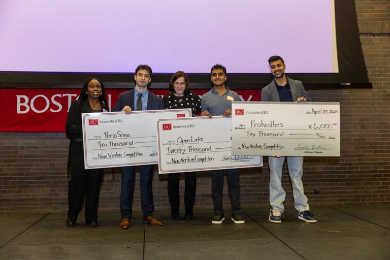 A group of student innovators holding their prize money checks on stage