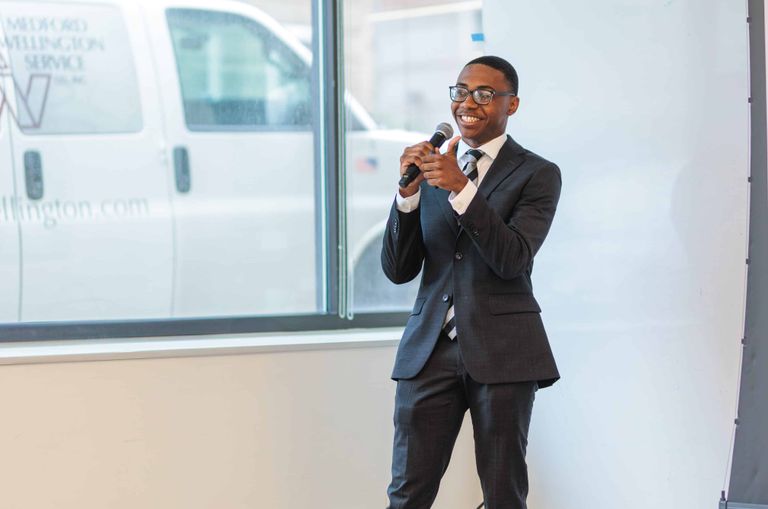 A student wearing a suit pitching during a demo day