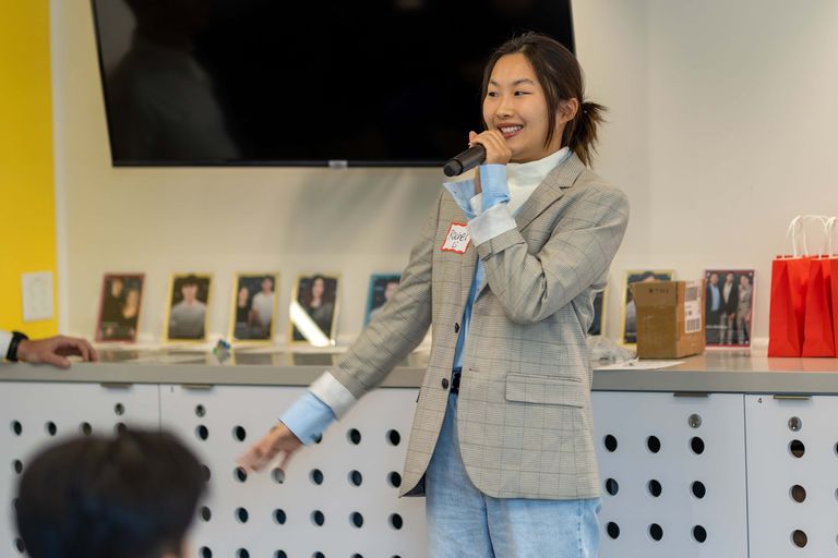 A woman standing giving a presentation with a microphone