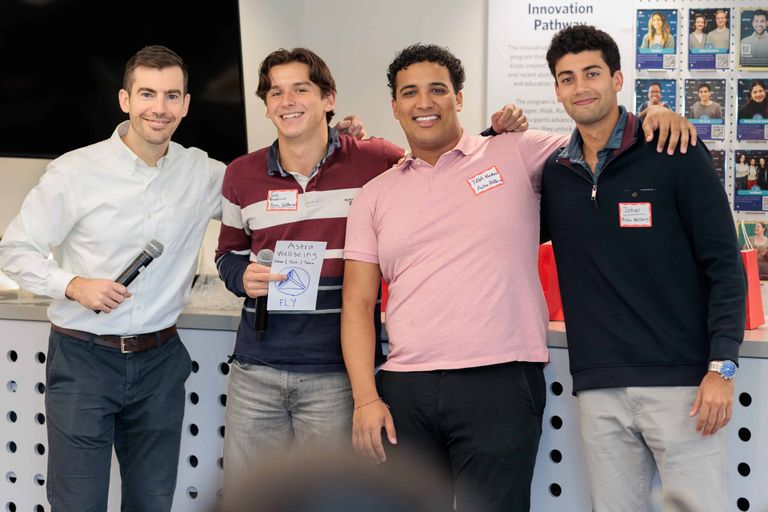 Four men stand together smiling after their presentation