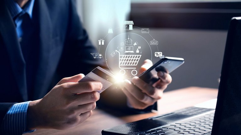 A man holding a smartphone in one hand and a payment card in the other, ready to make a digital transaction.