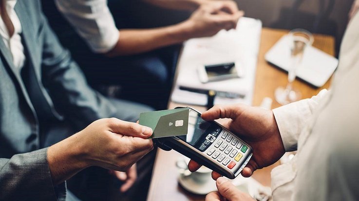 A businessman pays contactless with his credit card in a restaurant