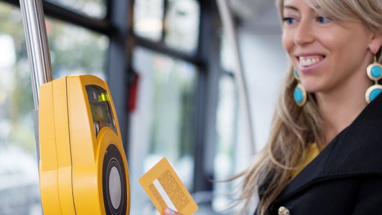 A woman pays contactless with a card in a public transportation system