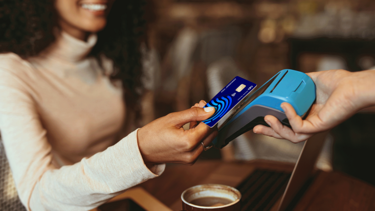 Photo of a woman holding her payment card to a payment device