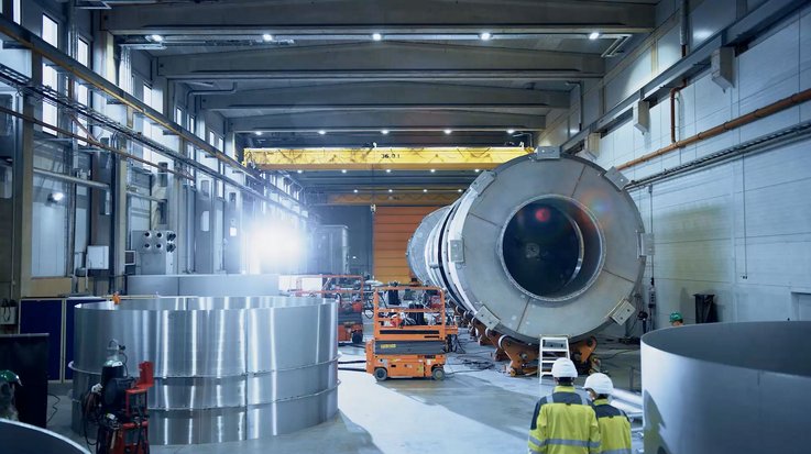 People in protective clothing cross a factory hall