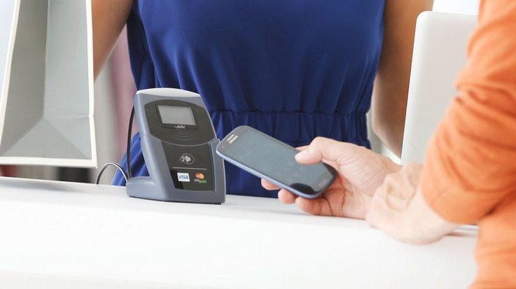 A person pays contactless with his smartphone in a clothing store