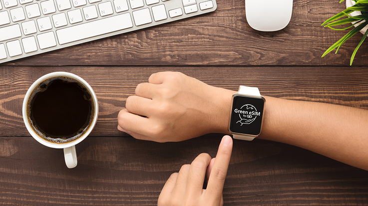 A person operates a smartwatch with the inscription "Green eSIM by G+D".