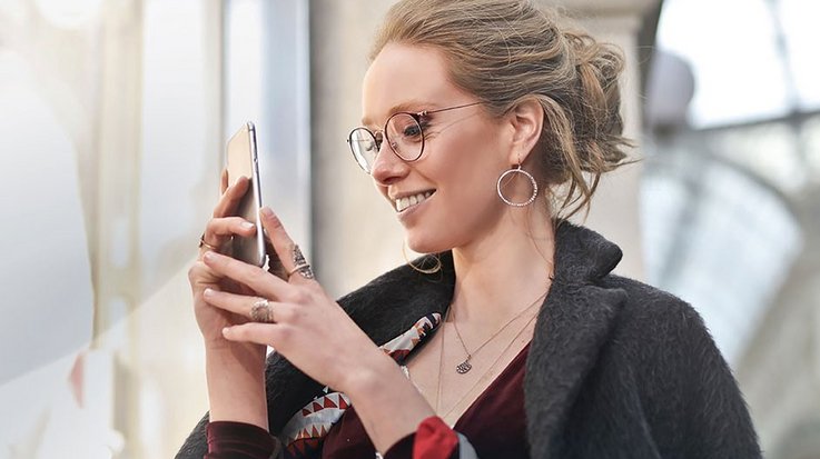 Smiling woman operates her smartphone