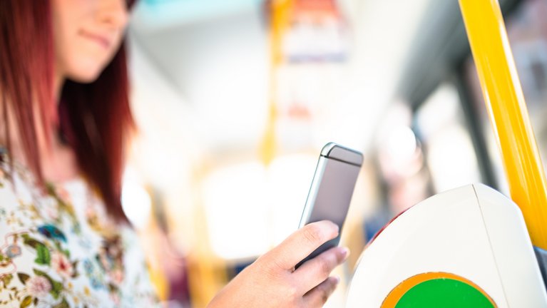 A woman pays for her ticket contactlessly with her smartphone on public transport