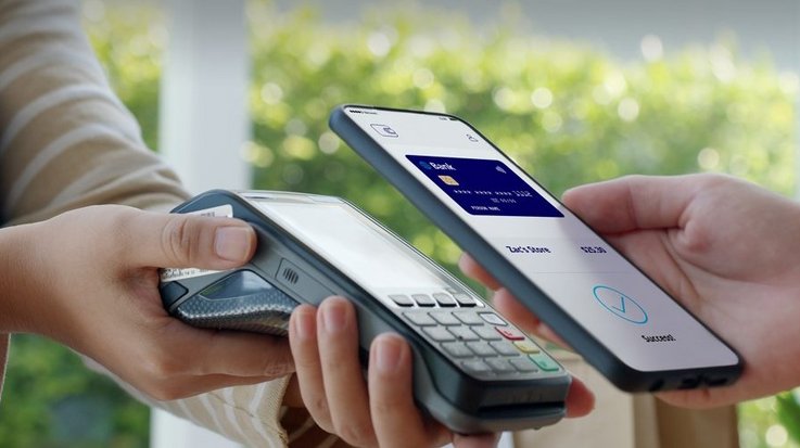 A person pays contactless with her smartphone, on the screen appears the image of a credit card 