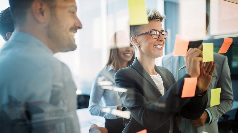 Two people working together and sticking notes on a board