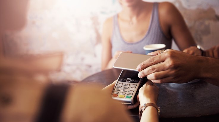 A person pays contactless with the smartphone in a café