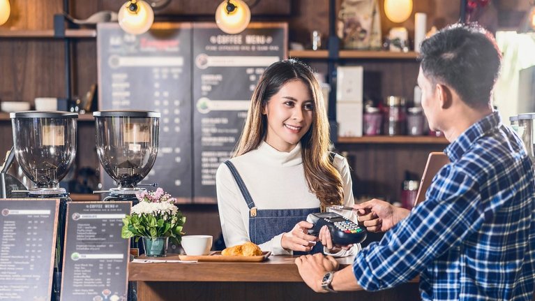 A man pays contactless with a credit card in a café