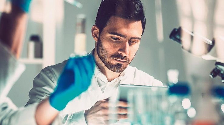 A man in a medical laboratory operates a tablet