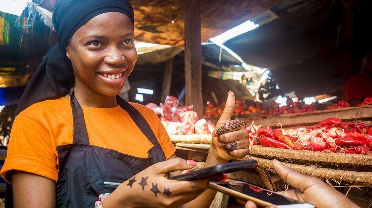 Woman uses a smartphone at the market to pay for goods.