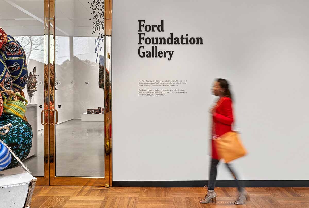 Woman in red coat walking toward Ford Foundation Gallery doors