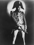 Paul Robeson dressed as a revolutionary from a 1936 production of Toussaint Louverture. He wears a Napoleonic hat and his hand rests on a sword.