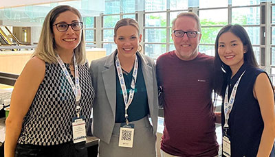 Four people standing together smiling at the camera.