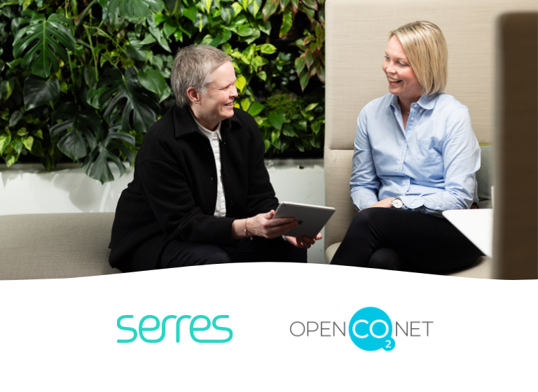 Two women talking and smiling in an office setting.