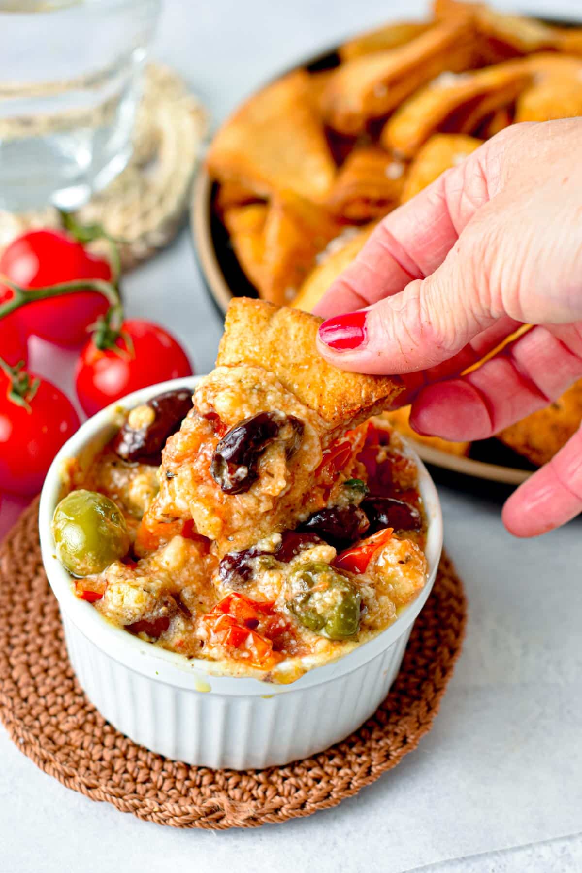 Dipping a pita chip into Baked Feta Dip.