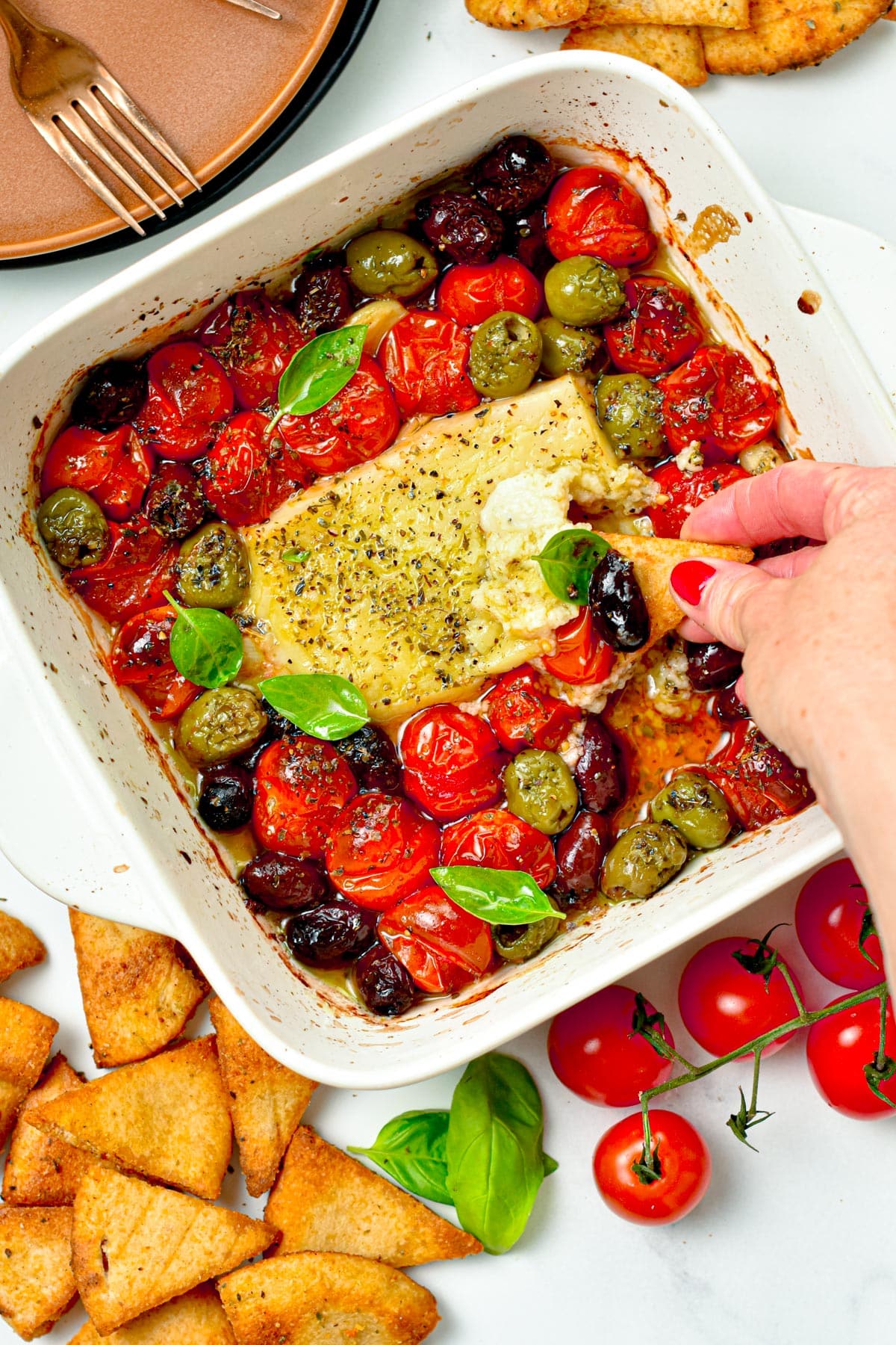 Baked Feta Dip on a ceramic dish with a pita crisp dipped into it.