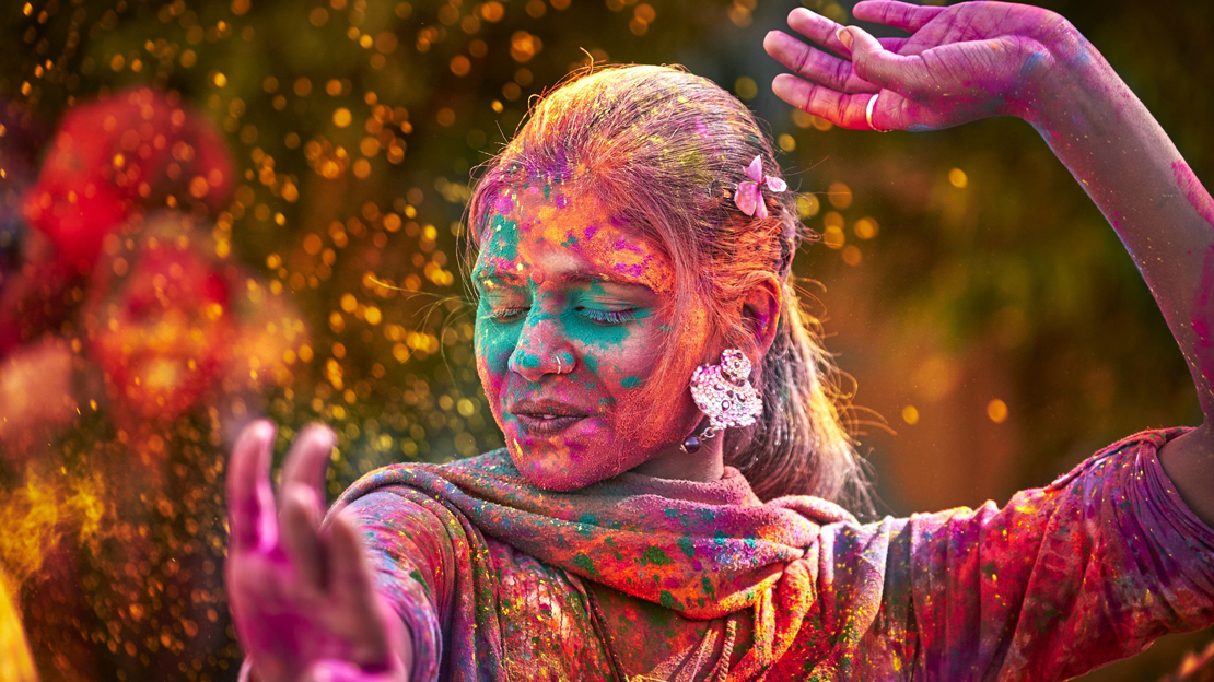 A woman covered in color, dancing.