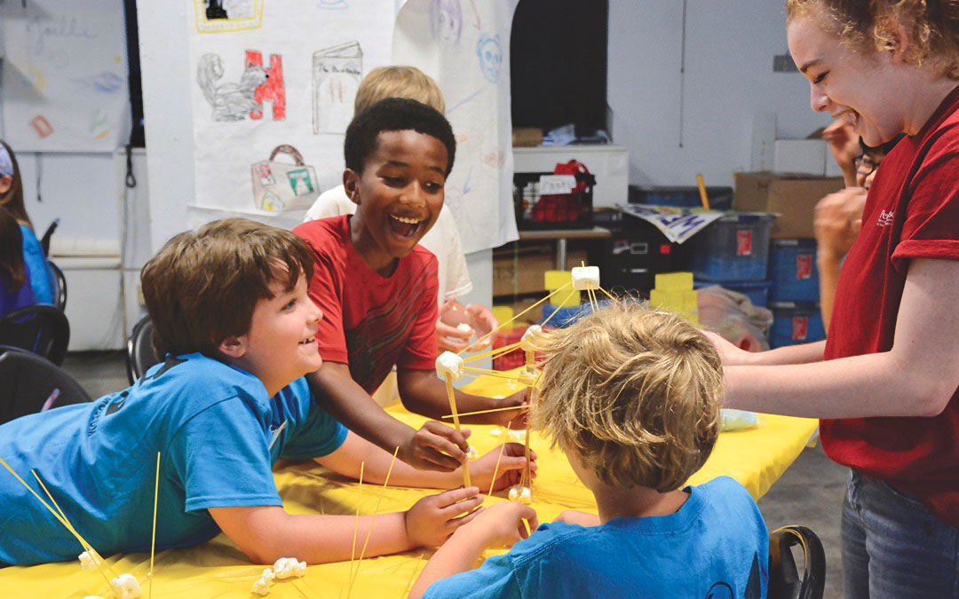 Campers building a structure out of spaghetti and marshmallows.