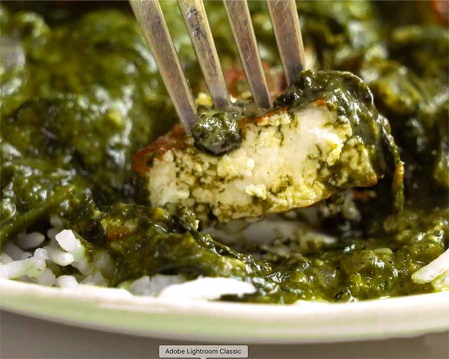 Fork picking up piece of Palak Paneer