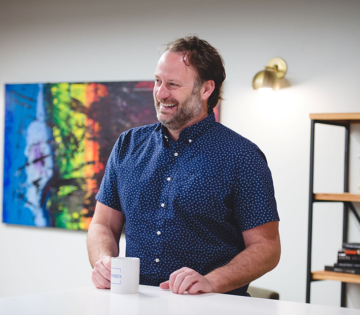 man smiling and holding a cup of Workbox coffee