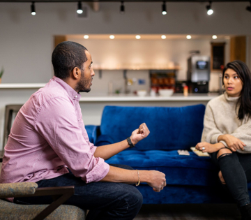 a man and a women in deep conversation sitting on a couch