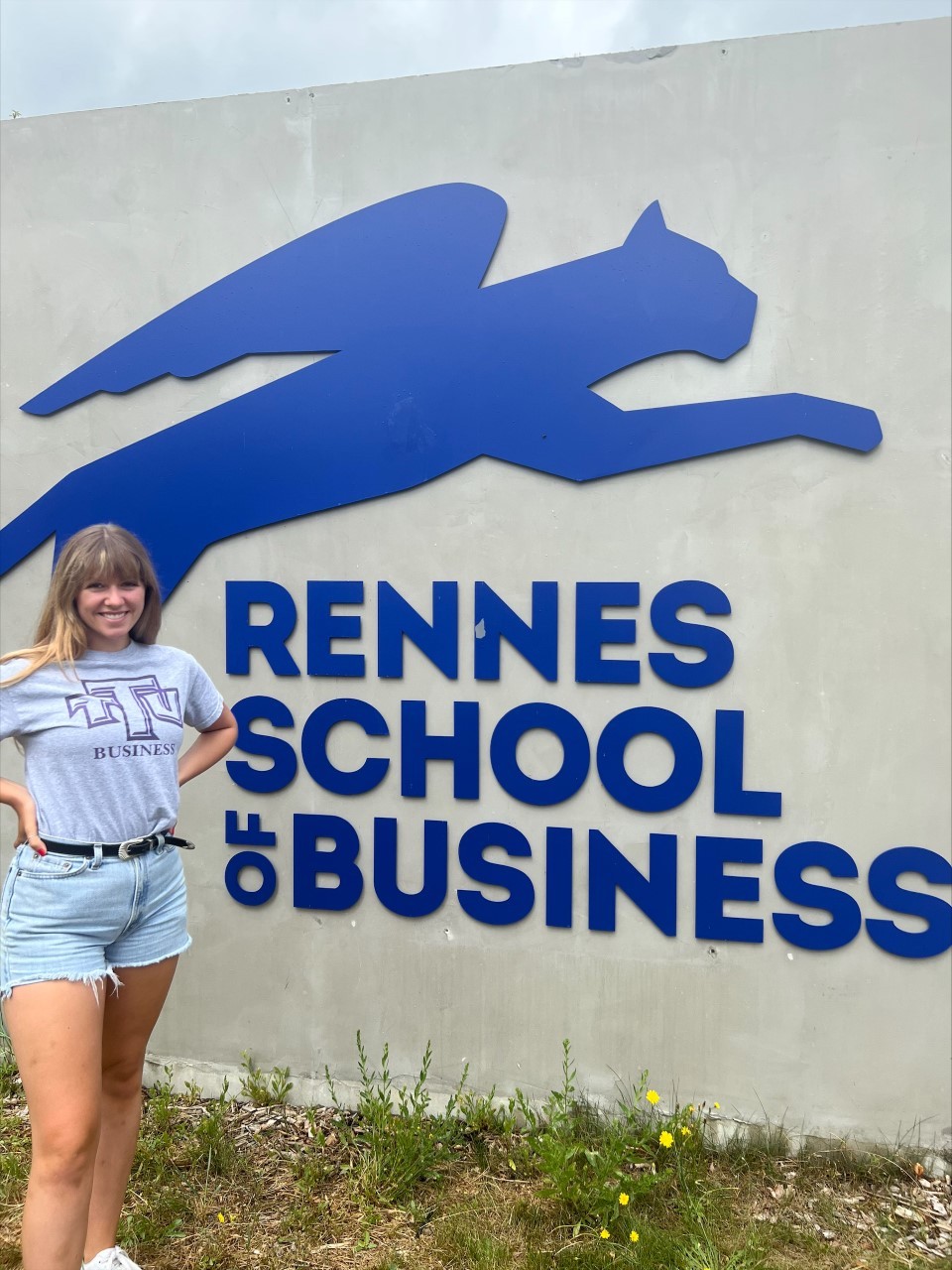 Student stands in front of Rennes School of Business sign