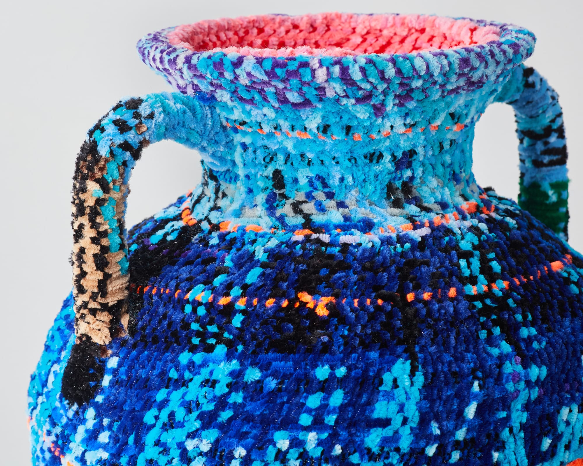 detail of a vessel made from woven pipe cleaners in shades of blue with pops of orange and pink