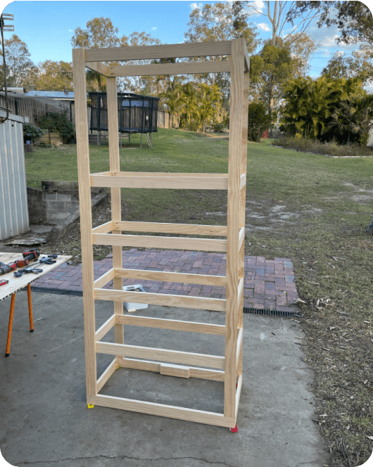 Partially constructed bookshelf wooden frame in a back yard