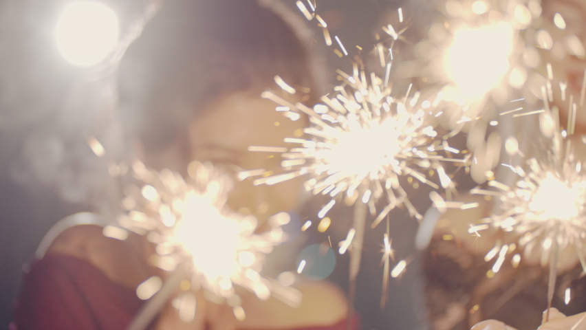 Closeup of hands lighting sparklers. Multiracial young people celebrate New YEAR Christmas Day, smile and laugh. Merry Christmas winter holiday concept. Friends spend time together. Festive emotional