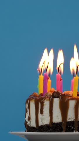 Lighted candles in a birthday cake rotation on a blue background. Candles in birthday cheesecake for home party.Copy space, Space for text