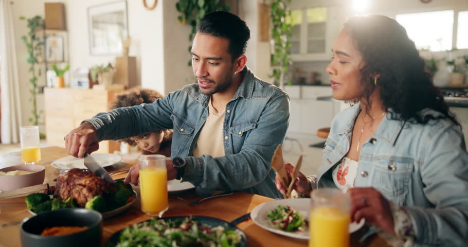 Family, lunch and man cutting chicken for sharing, dishing or support in dining room. Help, parents and child in home for healthy meal, portioning or woman choosing favorite piece for eating at table