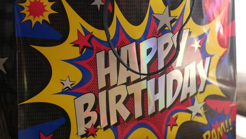 Woman pushes a Happy Birthday Bag toward camera at Birthday Party