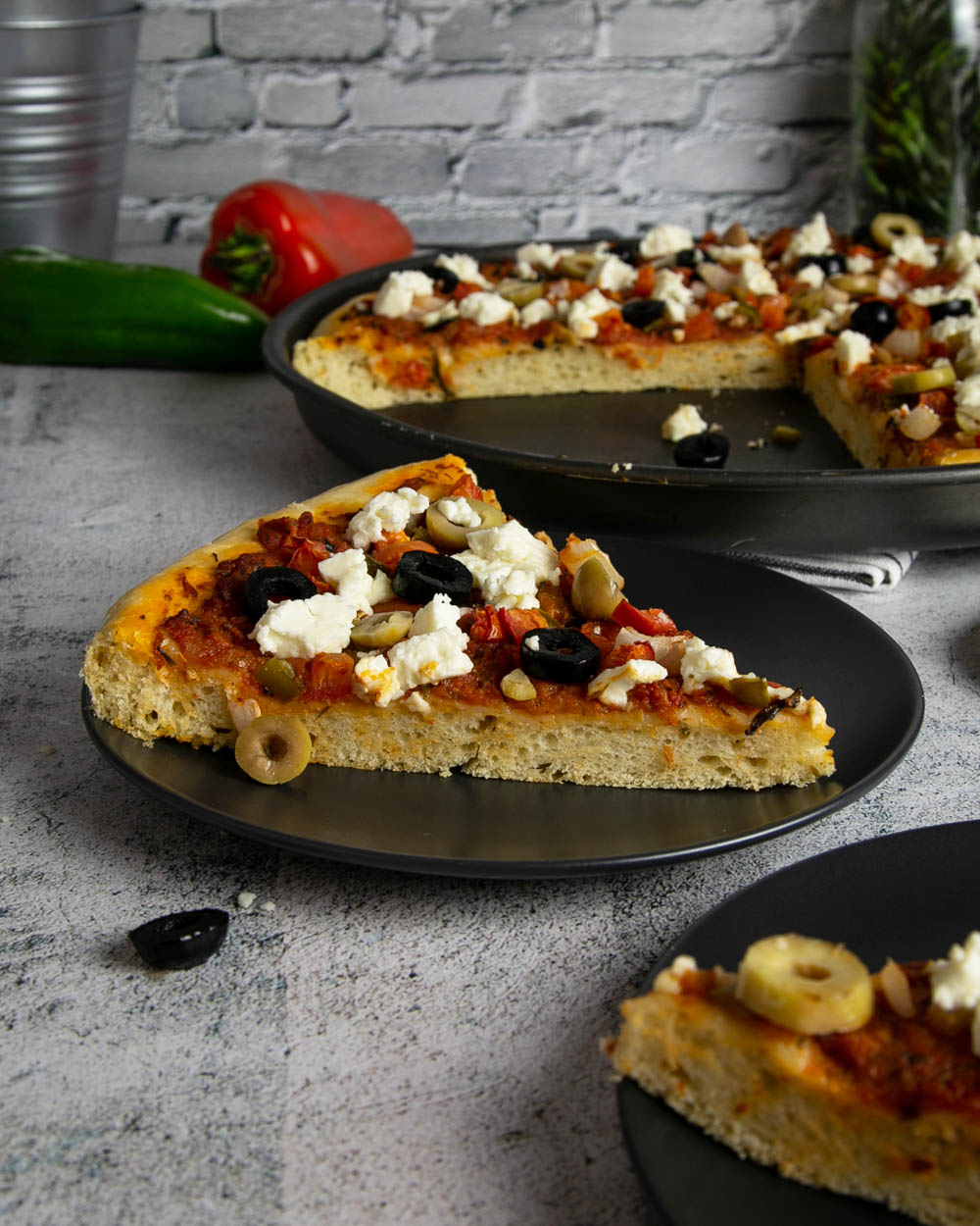 Side view of sliced Greek focaccia pizza topped with lots of olives and feta.