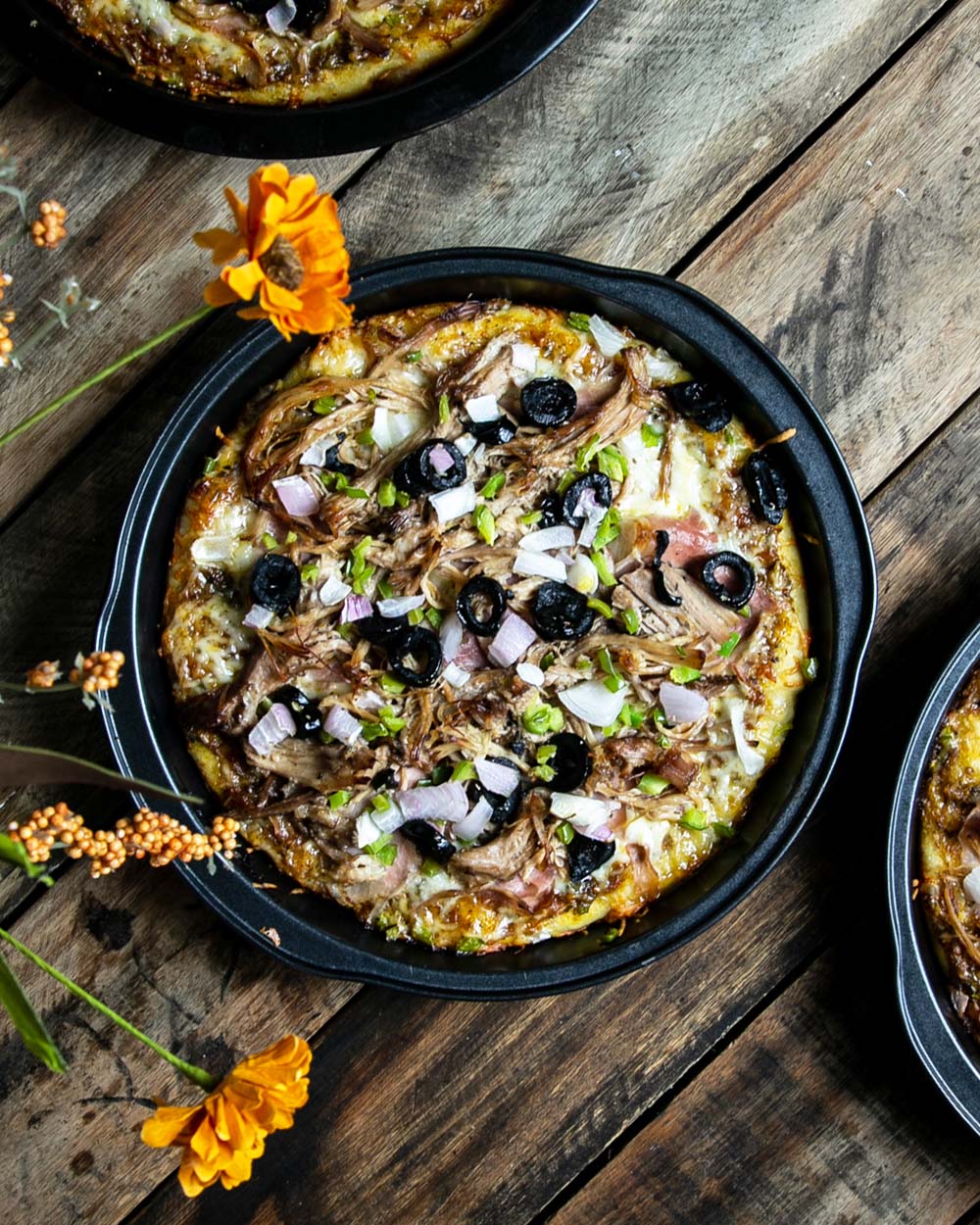 Top view of cuban pan pizza topped with mojo pork on a wooden background.