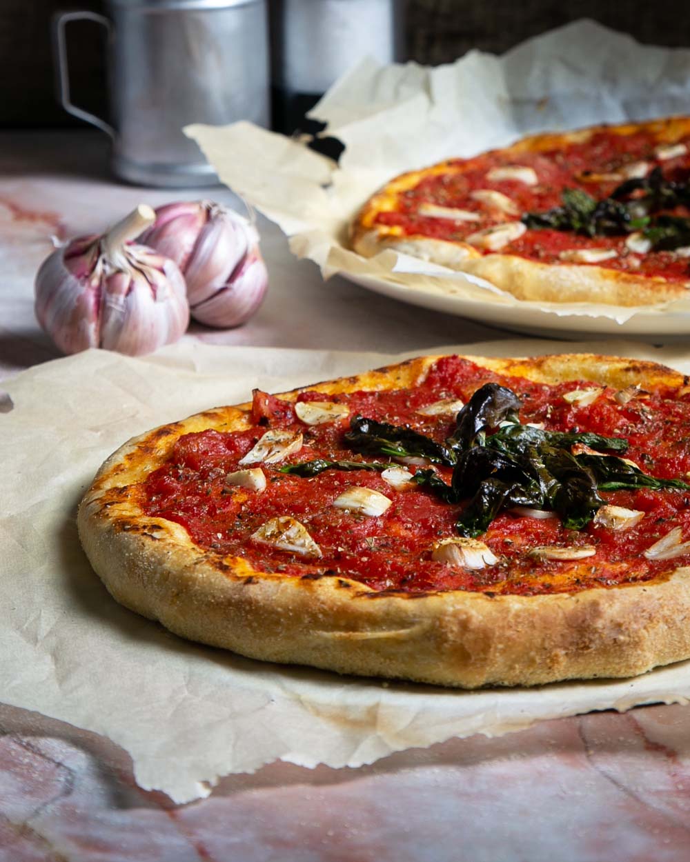 Side view of Pizza marinara on parchment paper with a light background