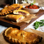 Calzone on a cutting board with marinara sauce