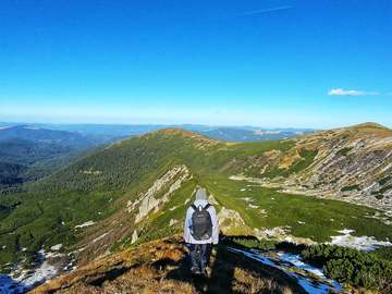 man standing at top of mountain overlooking city online puzzle